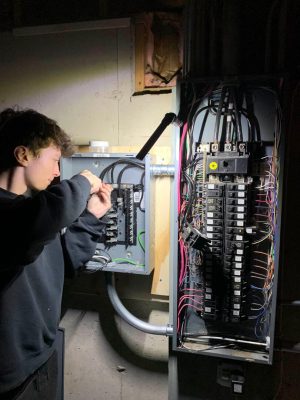 Photo of Tritan Services installing and upgrading an electrical service panel with a flashlight