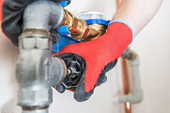 Photo of a person turning a plumbing valve